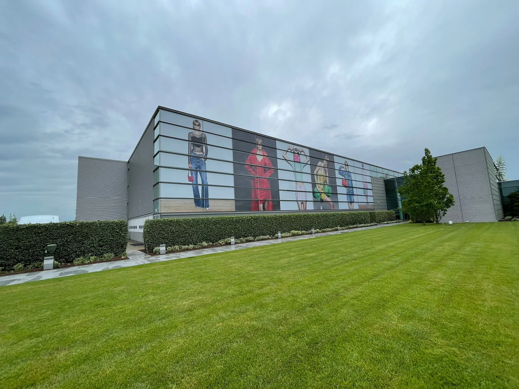 Vista complessiva dell’edificio PINKO con vetrofanie lungo la facciata e spazio verde antistante.
